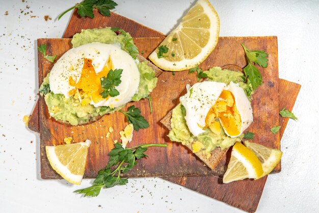 Sándwiches de dieta saludable para la merienda del desayuno Tostadas con salsa de guacamole, aguacate y huevo escalfado