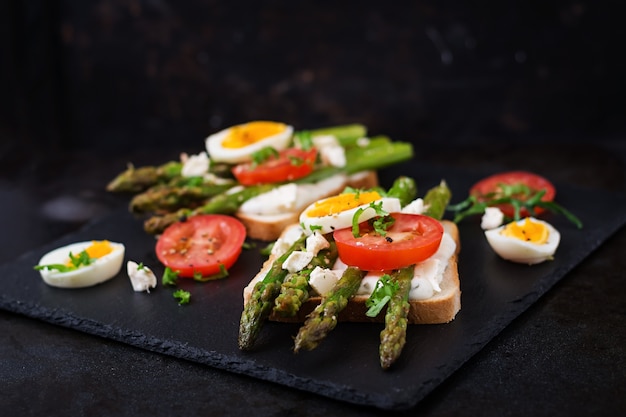 Sandwiches con espárragos caramelizados, queso feta, tomates y huevos.