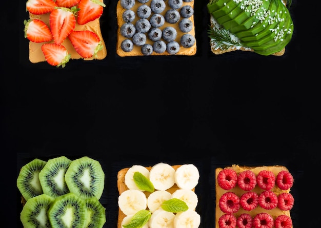 Foto sándwiches con frutas, bayas y verduras en el fondo negro copiar espaciovista superior