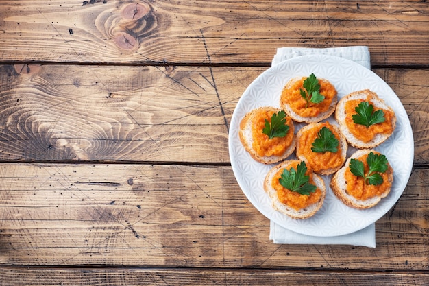 Sandwiches mit Brotzucchini-Kaviar-Tomaten-Zwiebeln. Hausgemachtes vegetarisches Essen. Geschmortes Gemüse in Dosen. Draufsicht des hölzernen Hintergrundes, Kopienraum