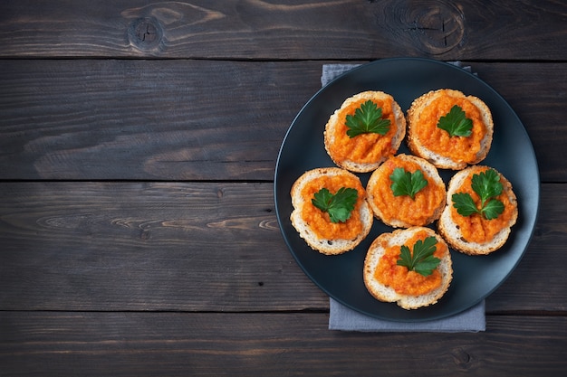 Sandwiches mit Brotzucchini-Kaviar-Tomaten-Zwiebeln. Hausgemachtes vegetarisches Essen. Geschmortes Gemüse in Dosen. Draufsicht des hölzernen Hintergrundes, Kopienraum