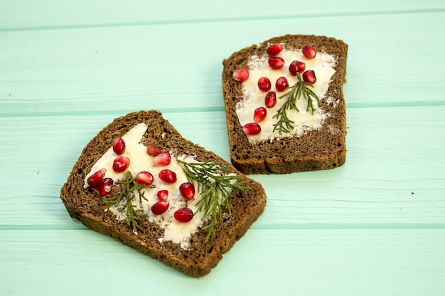 Sandwiches mit Butter und Beeren Granatapfel auf einem türkisfarbenen Hintergrund