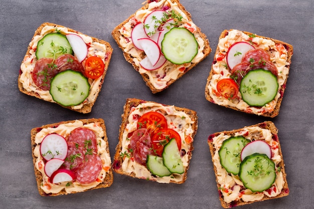 Sandwiches mit Frischkäse, Gemüse und Salami.