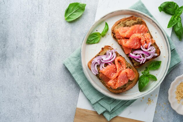 Sandwiches mit gesalzenem Lachs, Avocado, Guacamole, roten Zwiebeln und Basilikum Smorrebrod Satz dänischer offener Sandwiches Gesundes Frühstück Frühstück Clean Eating Diät veganes Ernährungskonzept Draufsicht