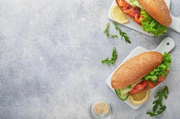 Sandwiches mit gesalzenem Lachs Offene Sandwiches aus Müsli oder Roggenvollkornbrot mit gesalzenem Lachs, Sesamsamen und getrockneten Tomaten auf weißem Marmorständer Meeresfrüchte Gesunde Ernährung Skandinavische Küche