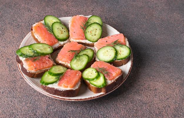 Sandwiches mit gesalzener Lachsgurke und Dill auf Weißbrot auf braunem Hintergrund