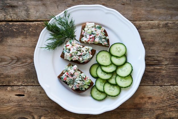 Sandwiches mit Gurken, Krabbenstangen und Gemüse auf einem Teller