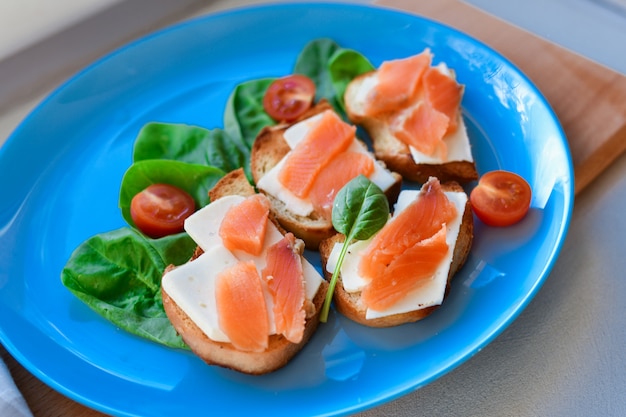 Sandwiches mit rotem Fisch auf einem blauen Teller. dekoriert mit Grüns