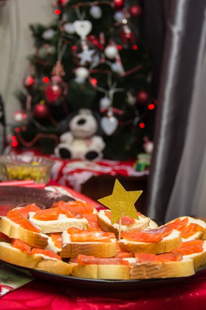 Sandwiches mit rotem Kaviar und Butter im Teller auf dem mit goldenem Weihnachtsstern dekorierten Tisch