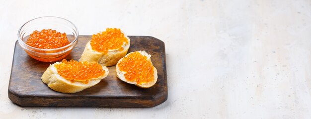 Sandwiches mit rotem Kaviar und Butter in Teller auf Holztisch. Draufsicht