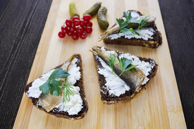 Sandwiches mit Sprotten und Viburnum-Beeren auf Holzbrett