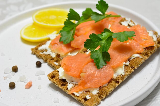 Sandwiches mit Weichkäse und Lachsscheiben, dekoriert mit Petersilie und Zitronenscheiben