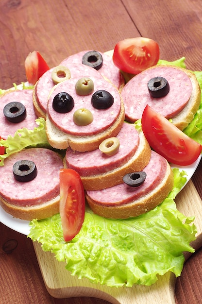 Sandwiches mit Wurst, Salat und Oliven auf einem Schneidebrett