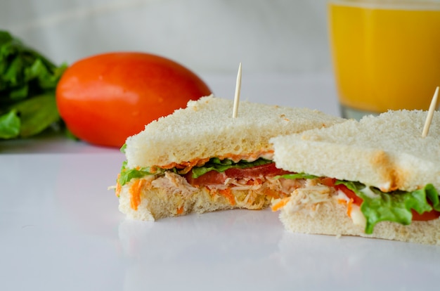 Sándwiches naturales en forma triangular y jugo de naranja sobre un fondo blanco