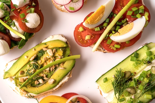 Sandwiches oder Tapas mit Brot, Frischkäse, Gemüse und leckeren Belägen.