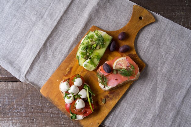 Sandwiches oder Tapas mit Brot, Frischkäse, Gemüse und leckeren Belägen.