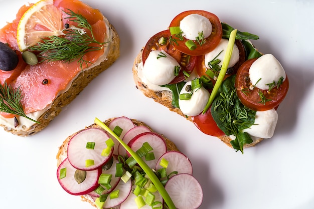 Sandwiches oder Tapas mit Brot, Frischkäse, Gemüse.