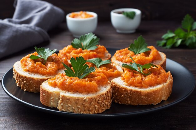 Sándwiches con pan calabacín caviar tomates cebollas. Comida vegetariana casera. Verdura guisada en conserva. fondo de madera de cerca