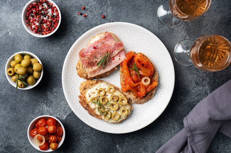 Sandwiches de pan integral con queso crema, tocino y aceitunas pimientos enlatados con tomate en un plato.