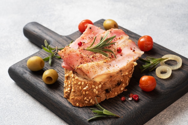 Sandwiches de pan integral con queso crema, tocino en una tabla para cortar madera.