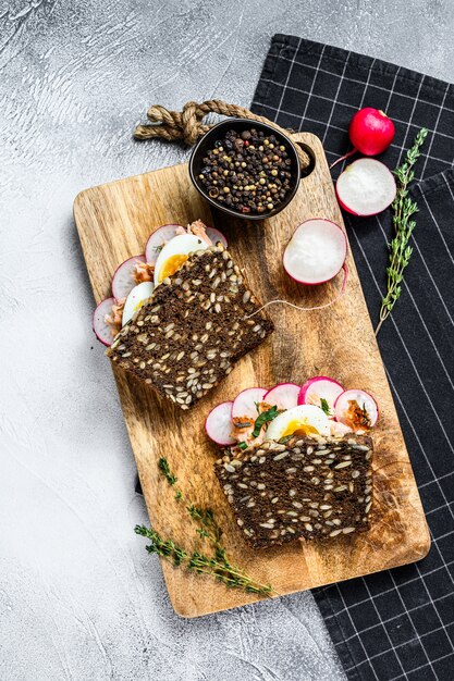 Sandwiches de pan integral con salmón ahumado caliente, huevos y rábanos. Comida sana y equilibrada., Vista desde arriba.