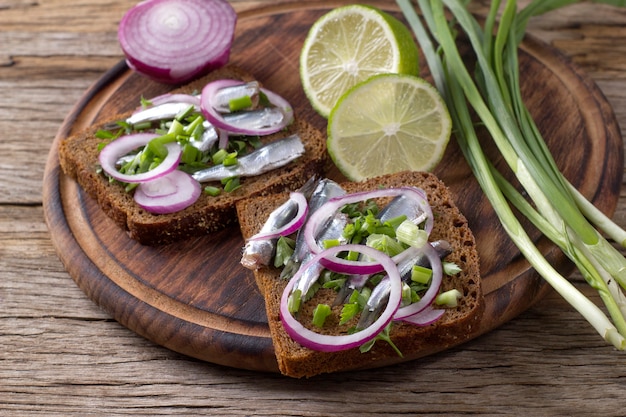 Foto sándwiches de pan negro con canales de espadín salado con cebolla y perejil