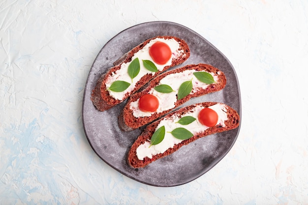 Foto sándwiches de pan de remolacha roja con queso crema y tomates en blanco