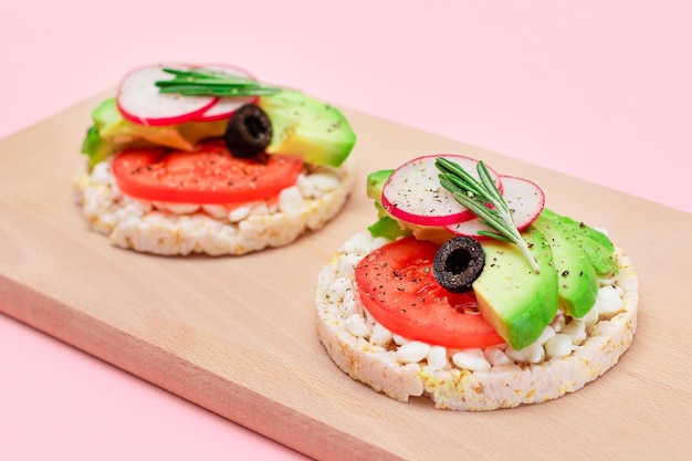 Sándwiches de pastel de arroz con aguacate, tomate, requesón, aceitunas y rábano