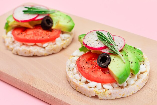 Sándwiches de pastel de arroz con aguacate, tomate, requesón, aceitunas y rábano