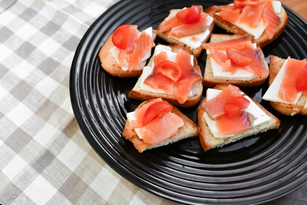 Sándwiches con pescado rojo en un plato negro. vista desde arriba