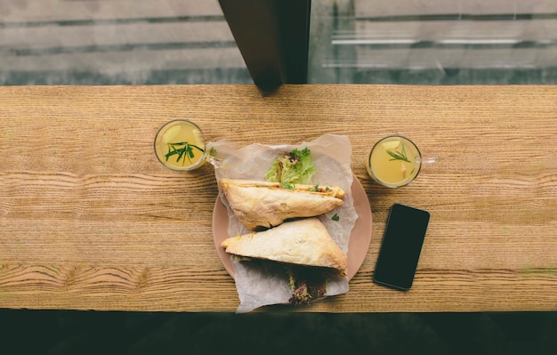 Foto sándwiches de pescado y salami, con té y celular