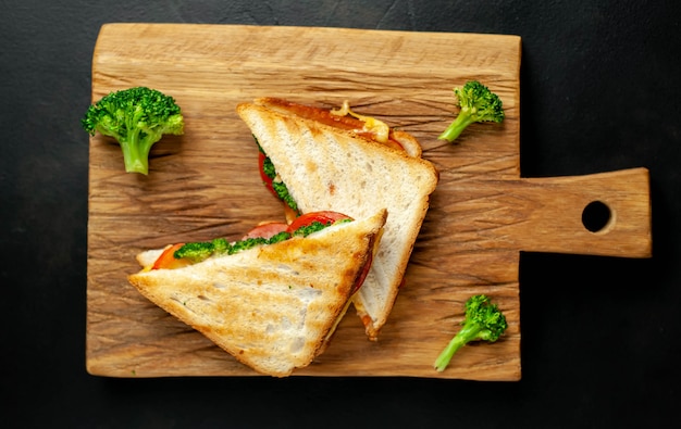 Sándwiches de queso de brócoli en tabla de cortar de madera, en concreto, fondo de pizarra