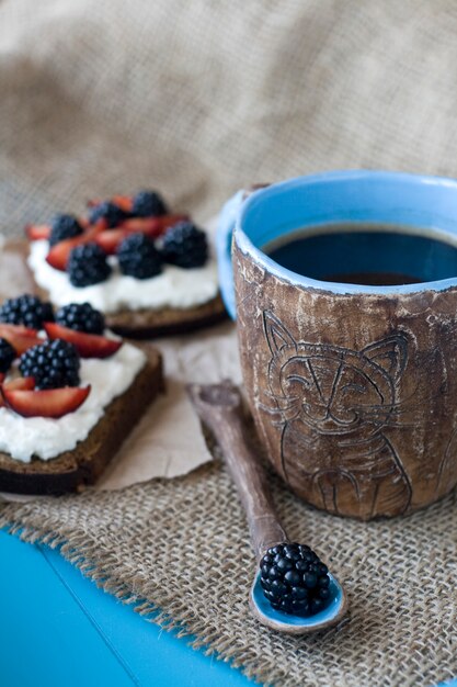 Sandwiches con queso dulce y bayas, una taza de café.