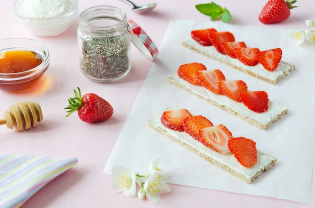 Sándwiches con requesón y fresas en el papel.