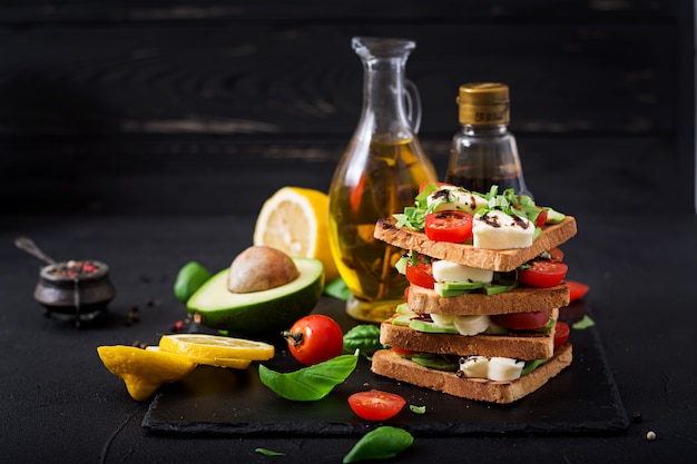 Sandwiches saludables con queso, tomate, aguacate y albahaca.