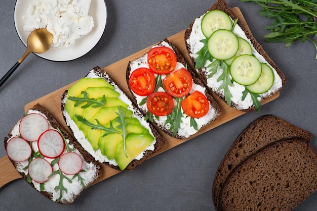 Sándwiches saludables con requesón blanco pepino rúcula aguacate tomate y rábano