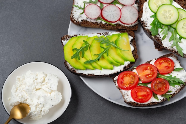 Sándwiches saludables con requesón blanco pepino rúcula aguacate tomate y rábano