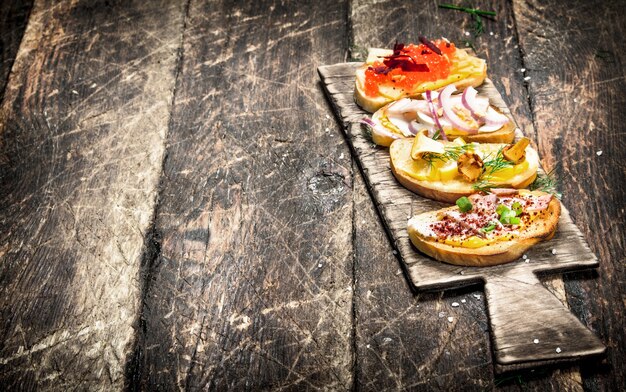 Sándwiches de setas, salami, caviar rojo y verduras frescas sobre pan tostado