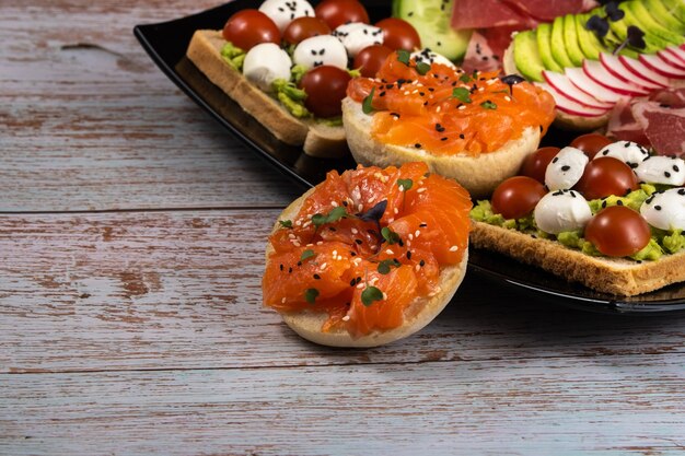 Sándwiches surtidos con pescado, queso, carne y verduras en una placa negra