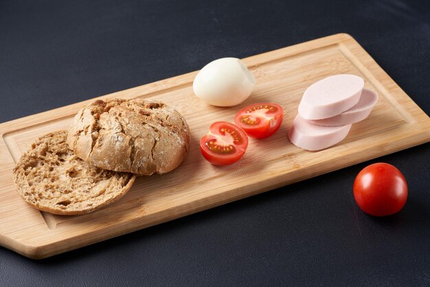 Foto sándwiches con tomates, huevos y mayonesa en un plato de madera