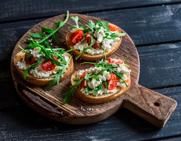 Sándwiches con tomates de queso ricotta y rúcula en una tabla de madera rústica