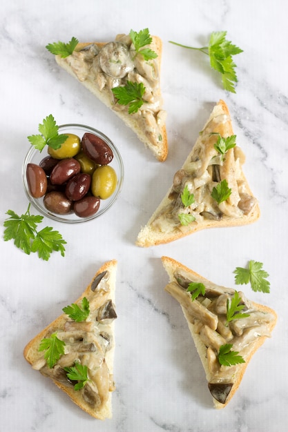 Sandwiches triangulares con champiñones de verano cocinados con crema y hierbas.