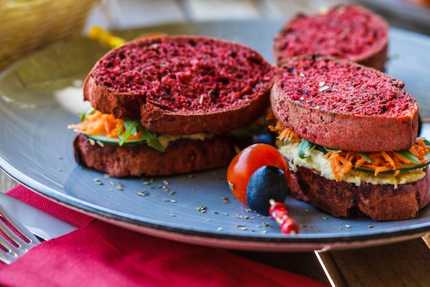 Sándwiches veganos para el desayuno con pan de remolacha, hummus y verduras.