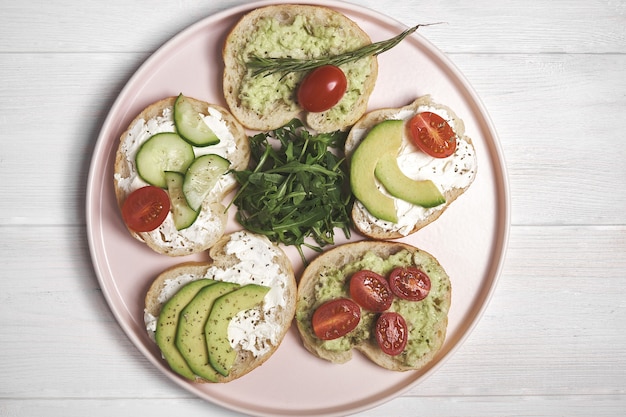 .Sándwiches veganos con requesón y verduras sobre fondo de madera.