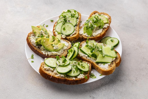 Sándwiches verdes vegetarianos con aguacate y pepino con microvegetales sobre un fondo claro