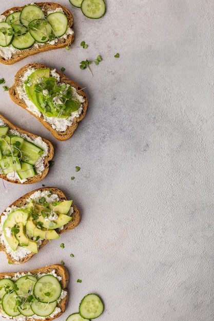 Sándwiches verdes vegetarianos con aguacate y pepino con microvegetales sobre un fondo claro