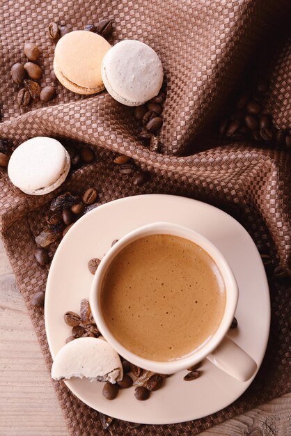 Sanfte bunte Makronen und Kaffee im Becher auf Holztischhintergrund