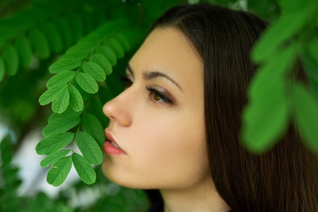 sanftes Bild mit Make-up einer schönen Frau in der Nähe von grünen Blättern