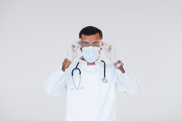 Sanitäter in Uniform Junger gutaussehender Mann, der drinnen vor weißem Hintergrund steht