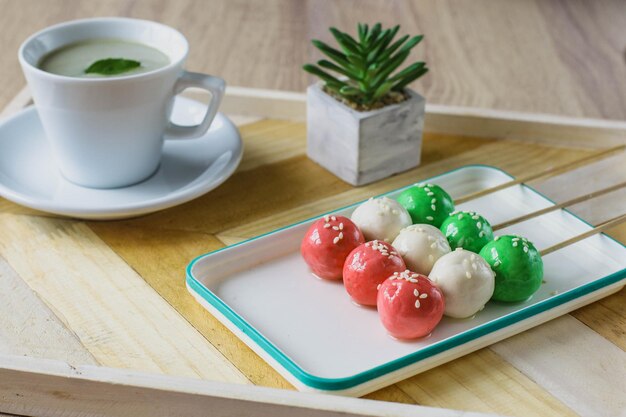 Sanshoku Dango três bolinhos coloridos com chá matcha servido na mesa de madeira